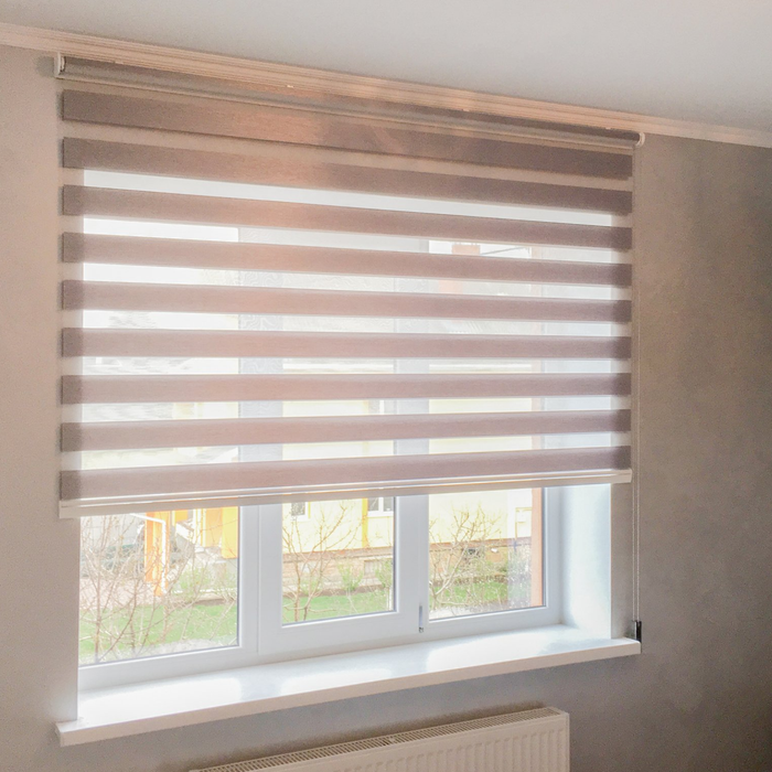 Close up of panelled roller blind half open on window looking out over garden area with building in the background.
