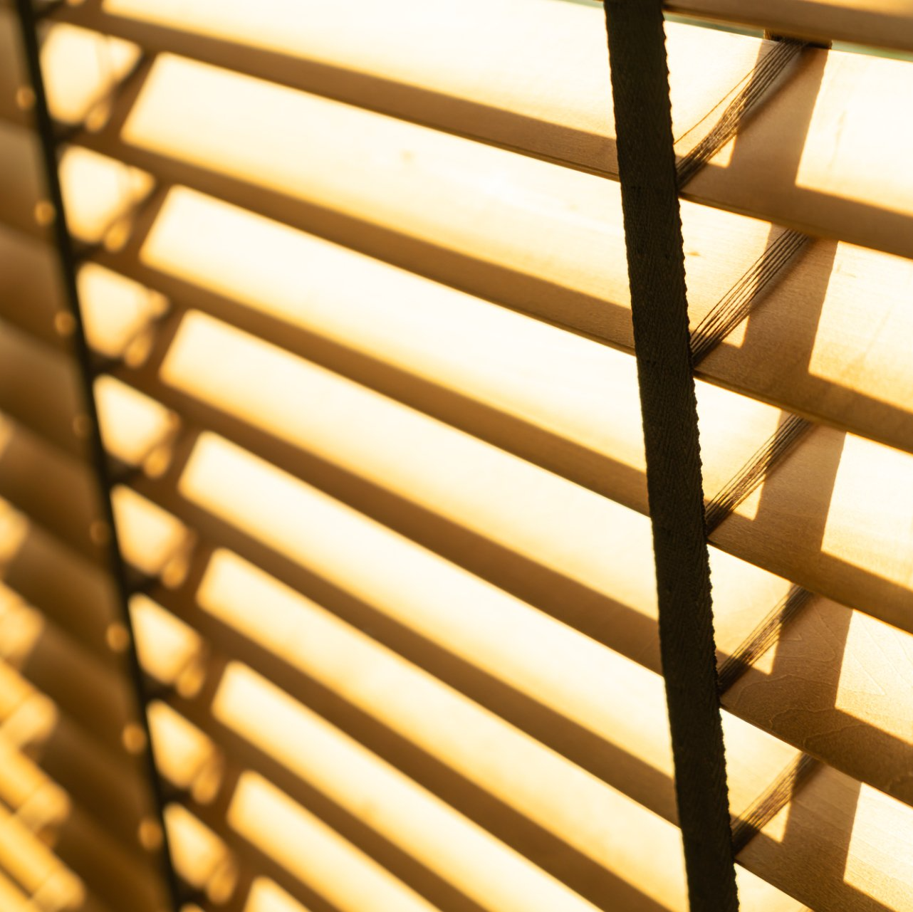 Close up of timber venetian blind, half open letting sunlight through.