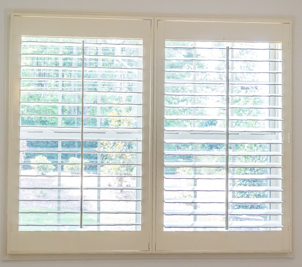 Close up of open plantation shutters, looking out over garden.