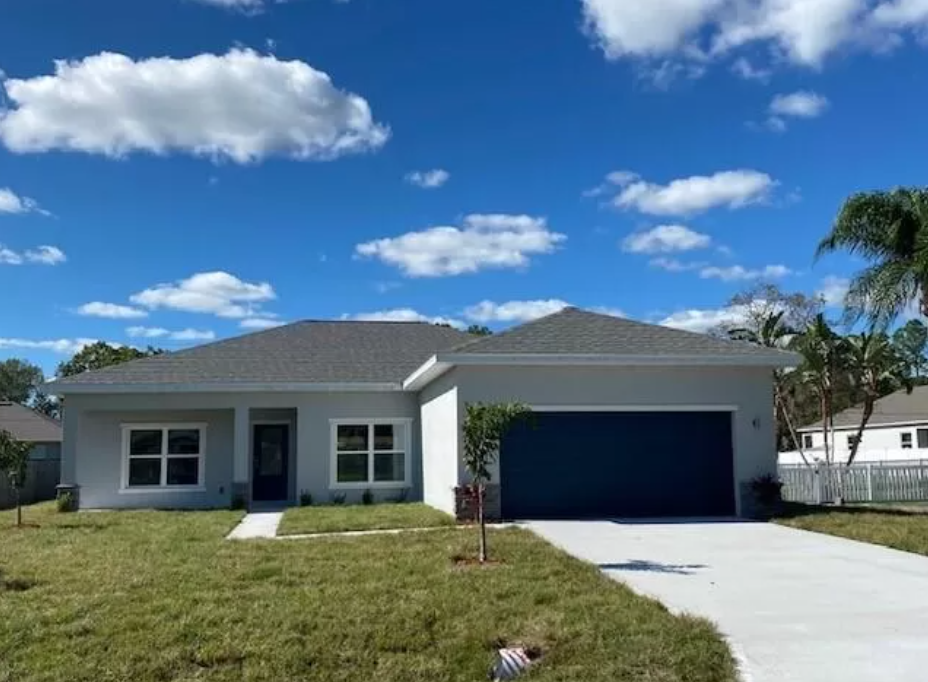 A white house with a blue garage door is for sale