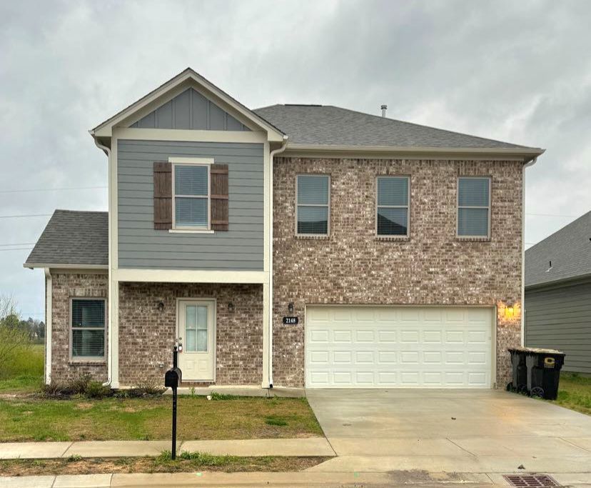 A large brick house with a white garage door is for sale.