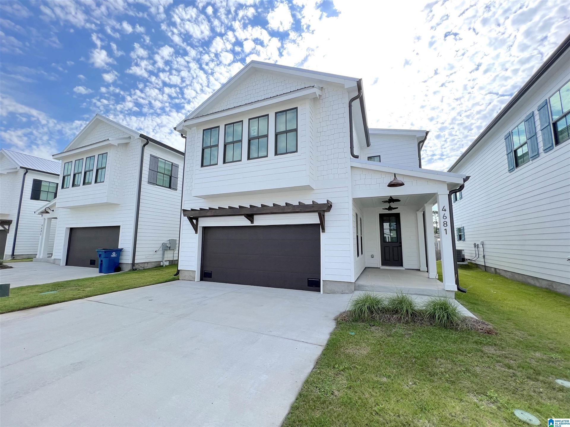 A white house with a black garage door is for sale.