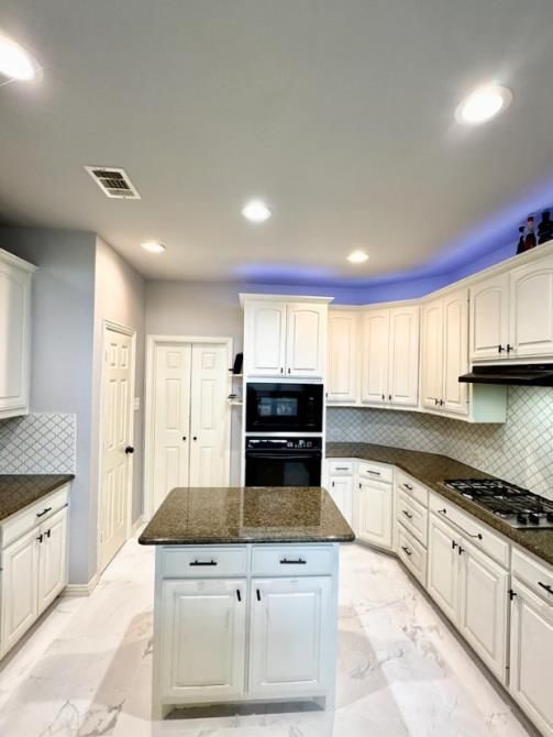 A kitchen with white cabinets and a large island in the middle.