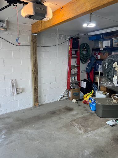 An empty garage with a ladder and a garage door opener.