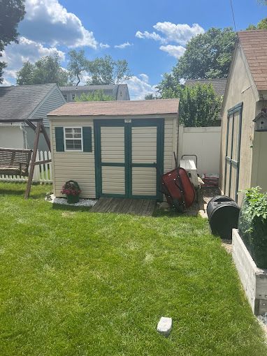 A small shed is sitting in the middle of a lush green yard.
