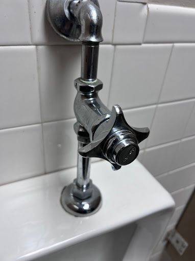 A close up of a urinal with a faucet attached to it.