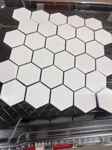A close up of a white hexagon tile on a black surface.
