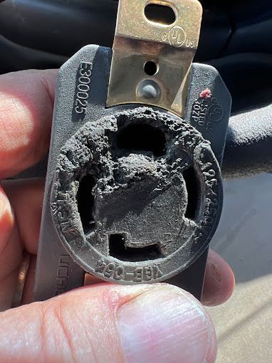 A person is holding a broken electrical outlet in their hand.