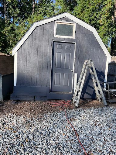 A shed with a door and a ladder in front of it.