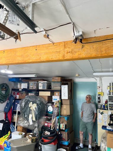 A man is standing in a garage filled with lots of boxes.