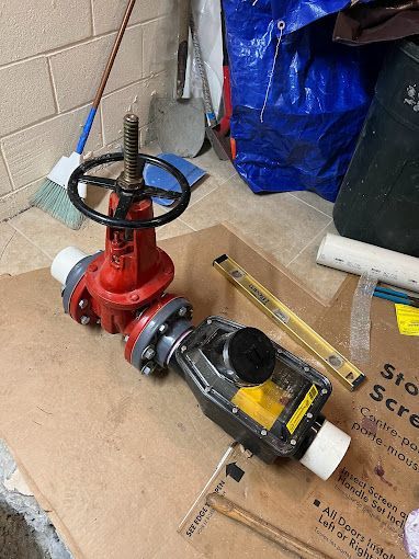A red valve is sitting on top of a cardboard box next to a level.
