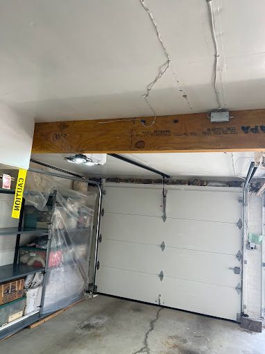 A garage with a white garage door and a wooden beam.