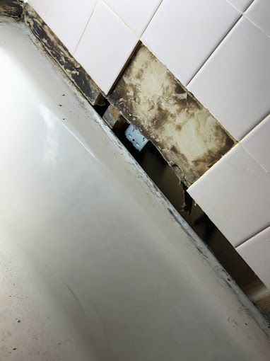 A bathtub is sitting in a bathroom next to a tiled wall.