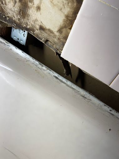 A close up of a bathroom sink with a broken tile.