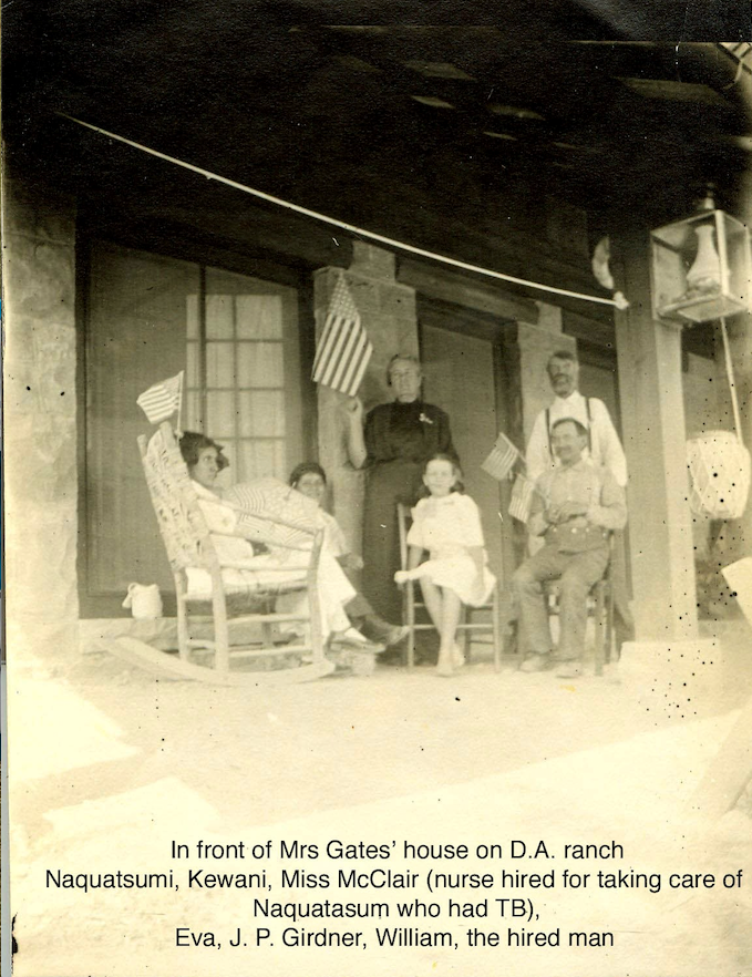 Group of people on a porch, holding flags; identified: Mrs. Bates, Naquatsumi, Kent, Miss McClair, Eve, J.P. Girdner, William.