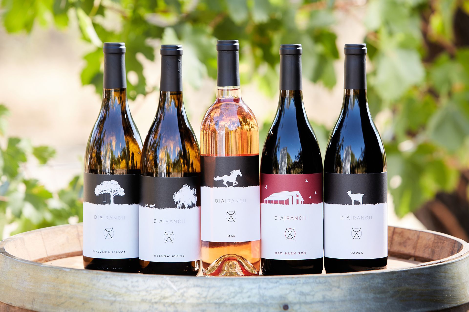 Five wine bottles on a barrel; labels feature animal silhouettes.