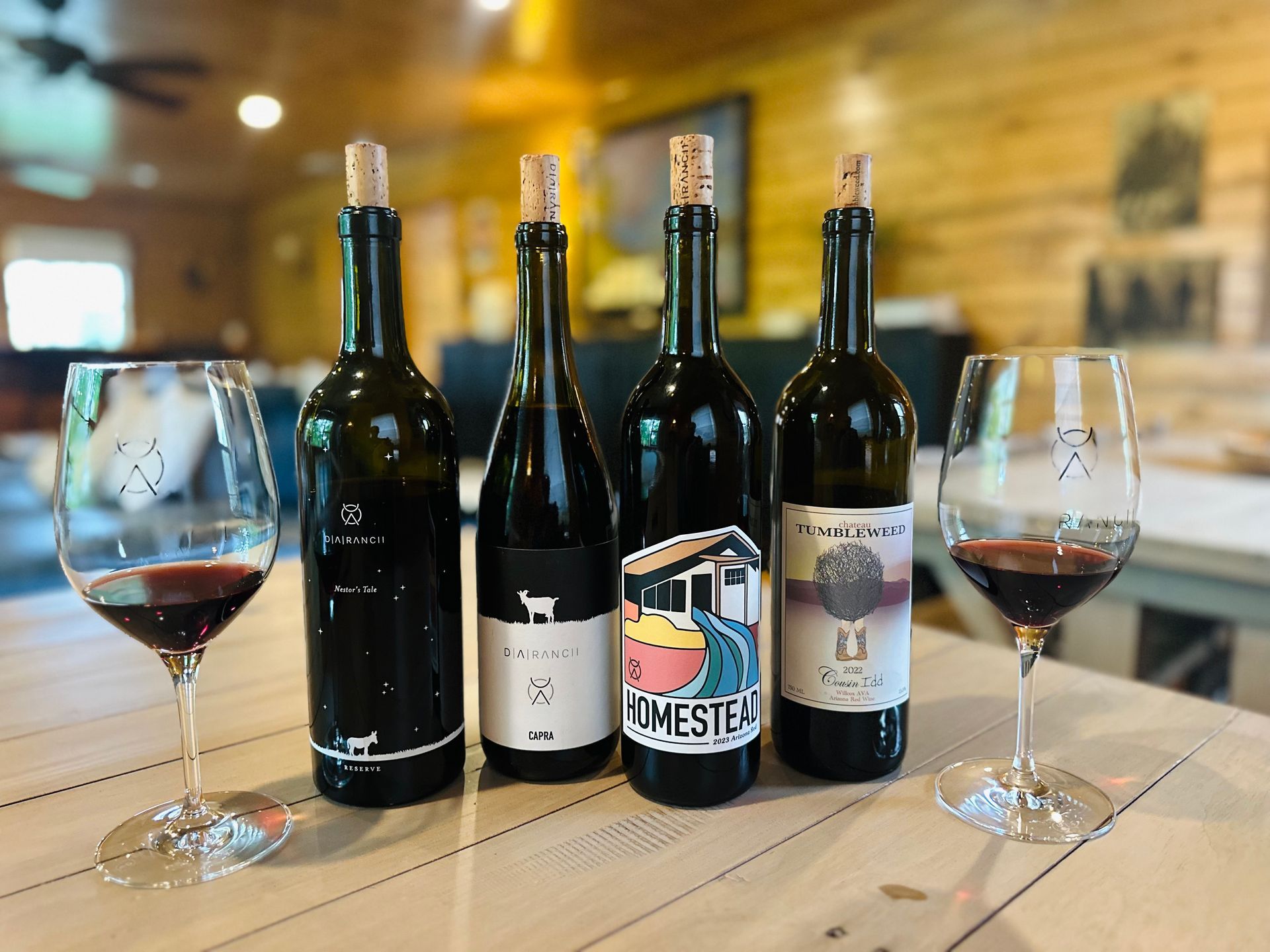 Group of people at a vineyard, some holding wine glasses. Woman in purple jacket smiles, looking at the camera.