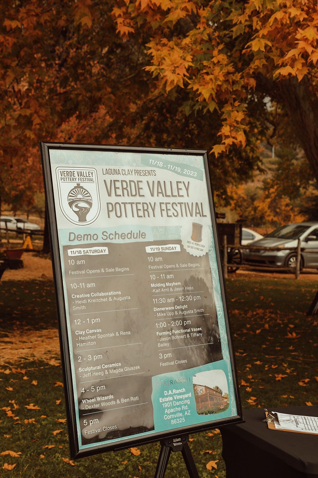 Sign for the Verde Valley Pottery Festival in front of fall trees, schedule visible.