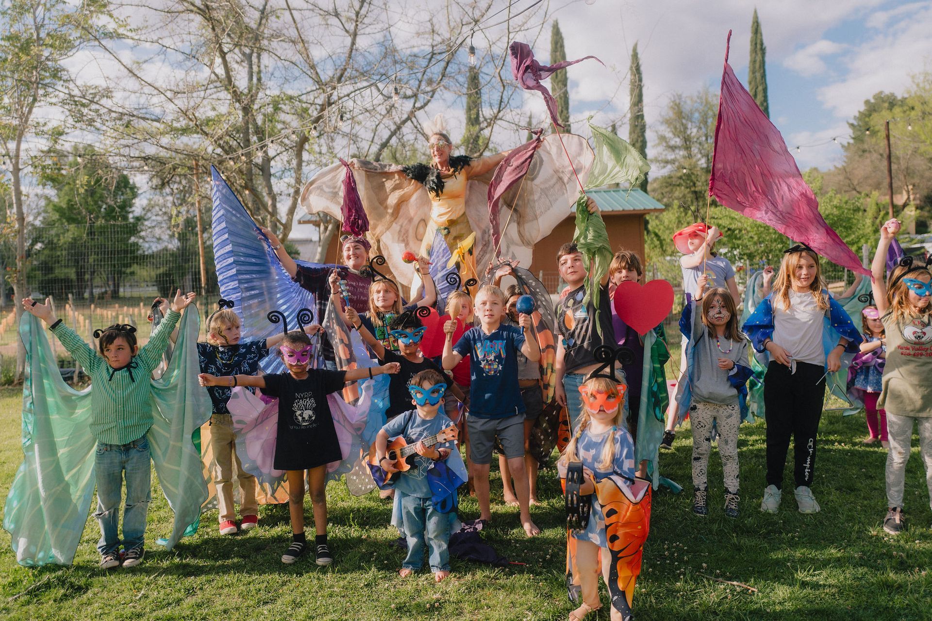 Group of children with costumes and wings in a park.