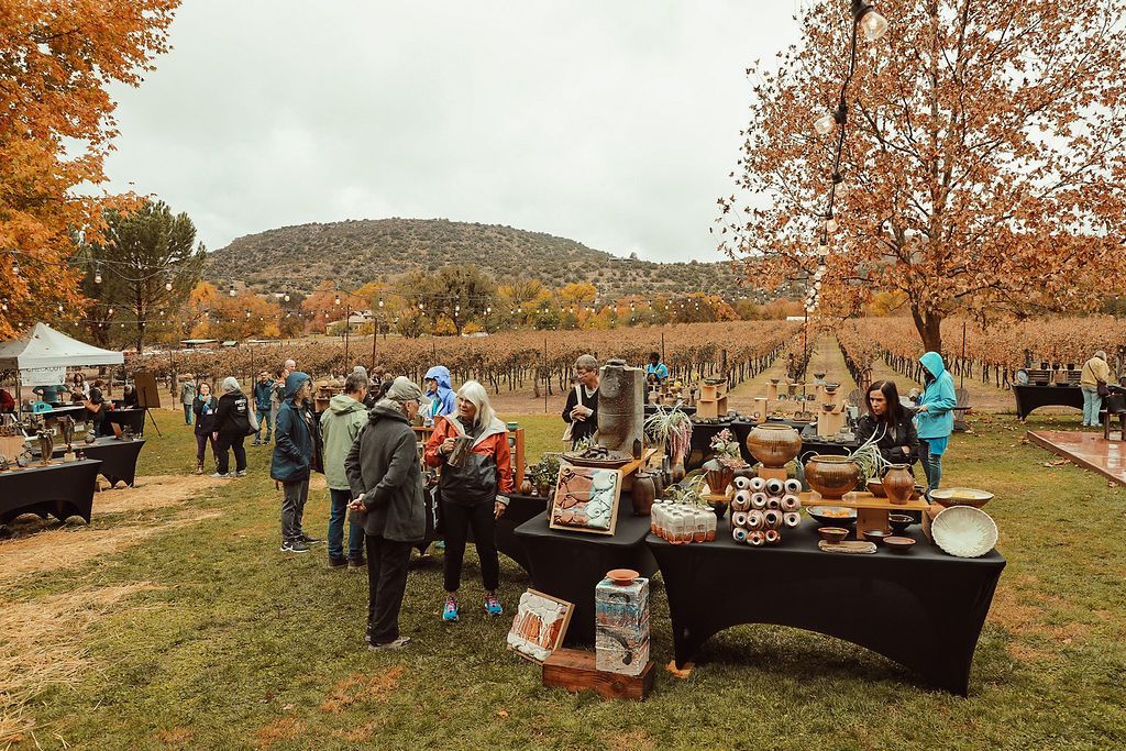 Art fair in a field with vendors, fall colors, and people browsing.