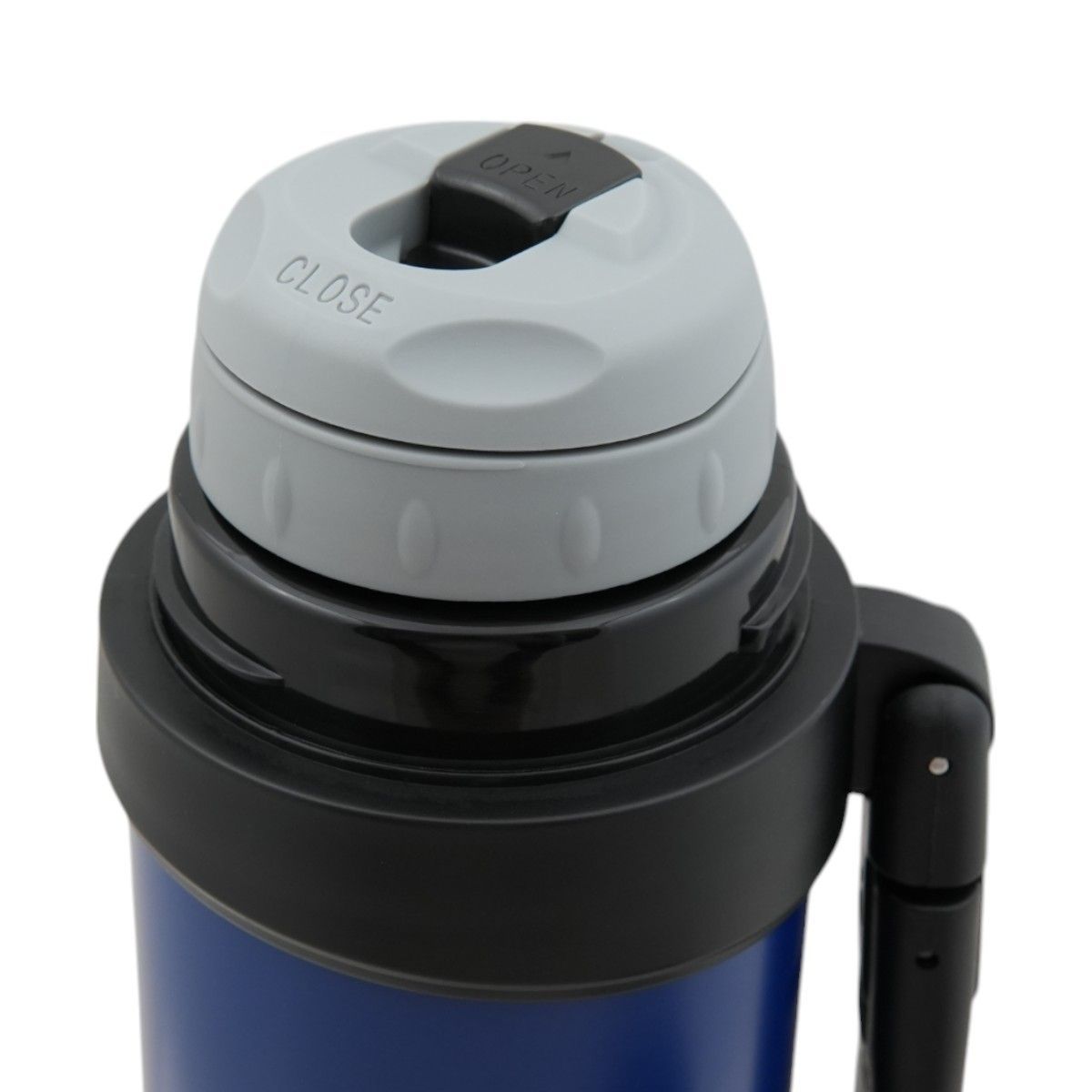 Termo azul con asa negra sobre una mesa de madera en un campo de hierba.