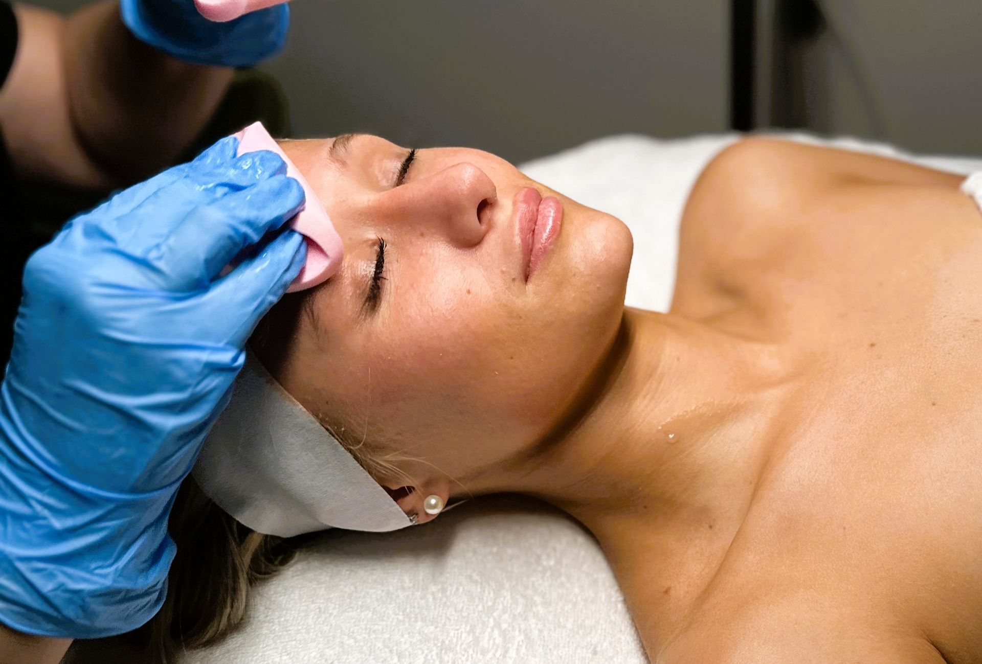 Close-up of a person lying down with a white foamy face mask applied.