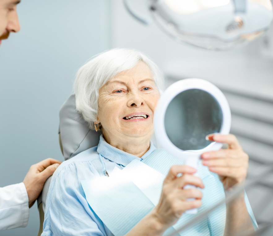 Smiling patient holding a mirror during a dental exam in a bright clinic