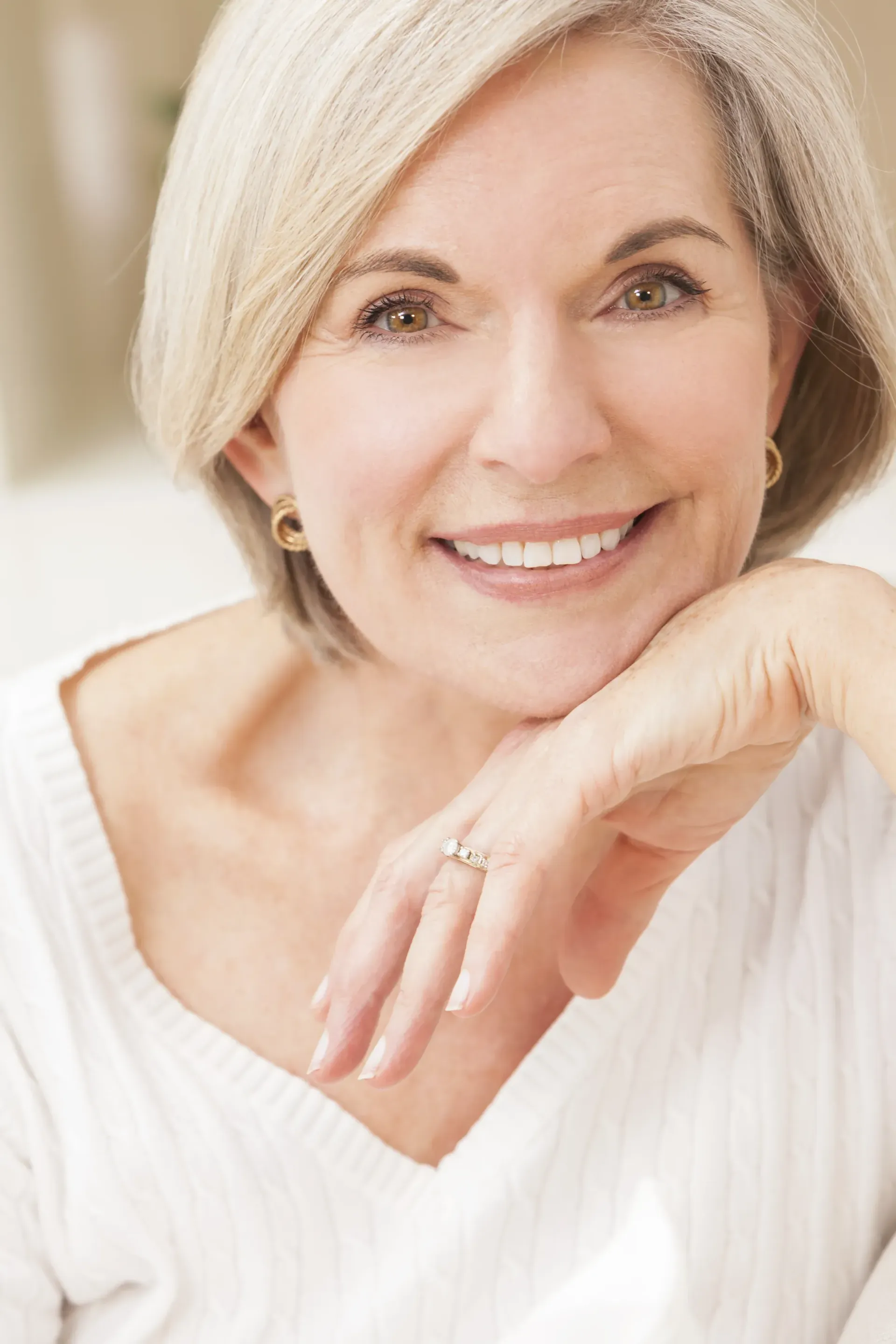 Smiling Person With Short Blonde Hair in a White Top, Resting Chin on Hand — Smiles On Hobart in Hobart, TAS