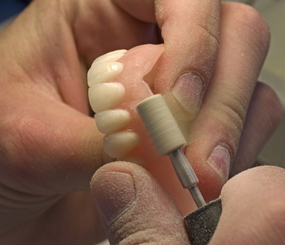 Dental Technician Polishing a White Denture With a Rotary Tool — Smiles On Hobart in Moonah, TAS