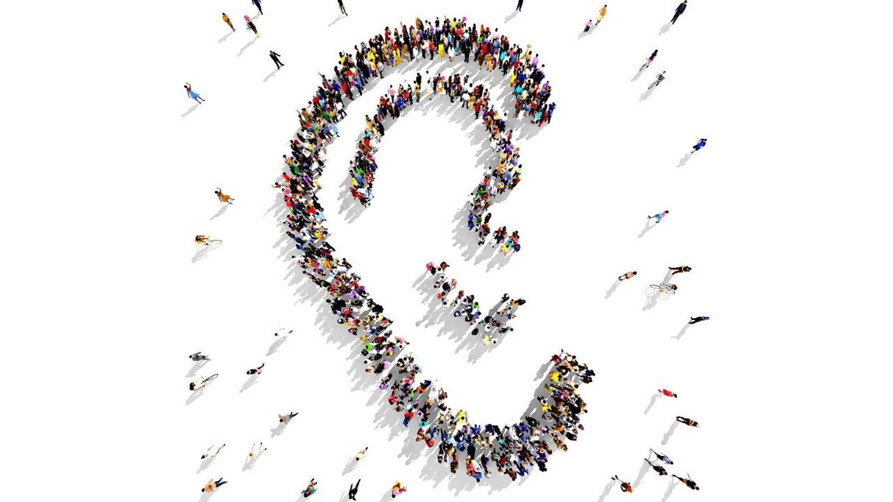 People arranged to form a symbolic ear on a white background.