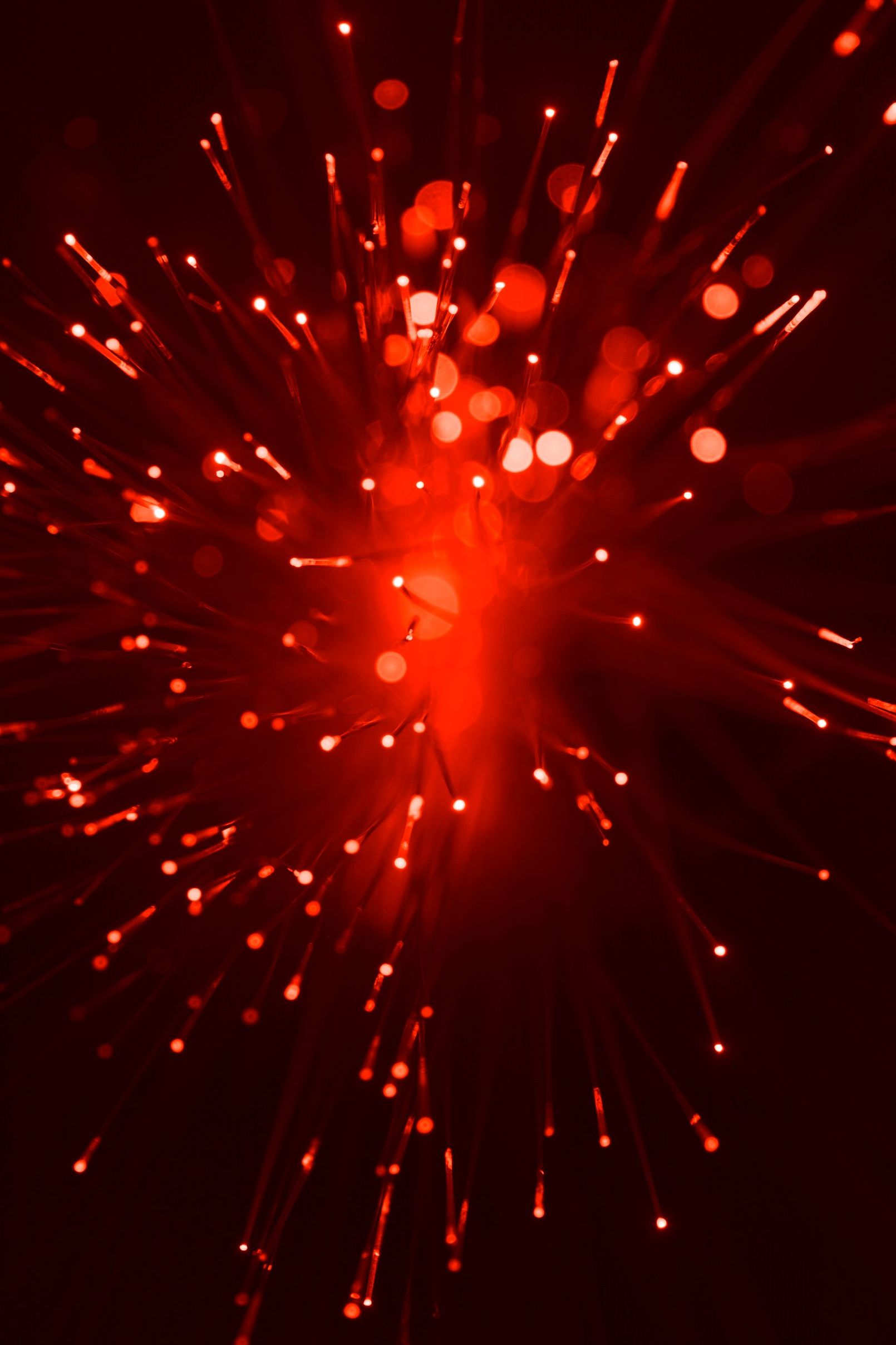 Red, glowing burst of light with radiating strands and bokeh effect.