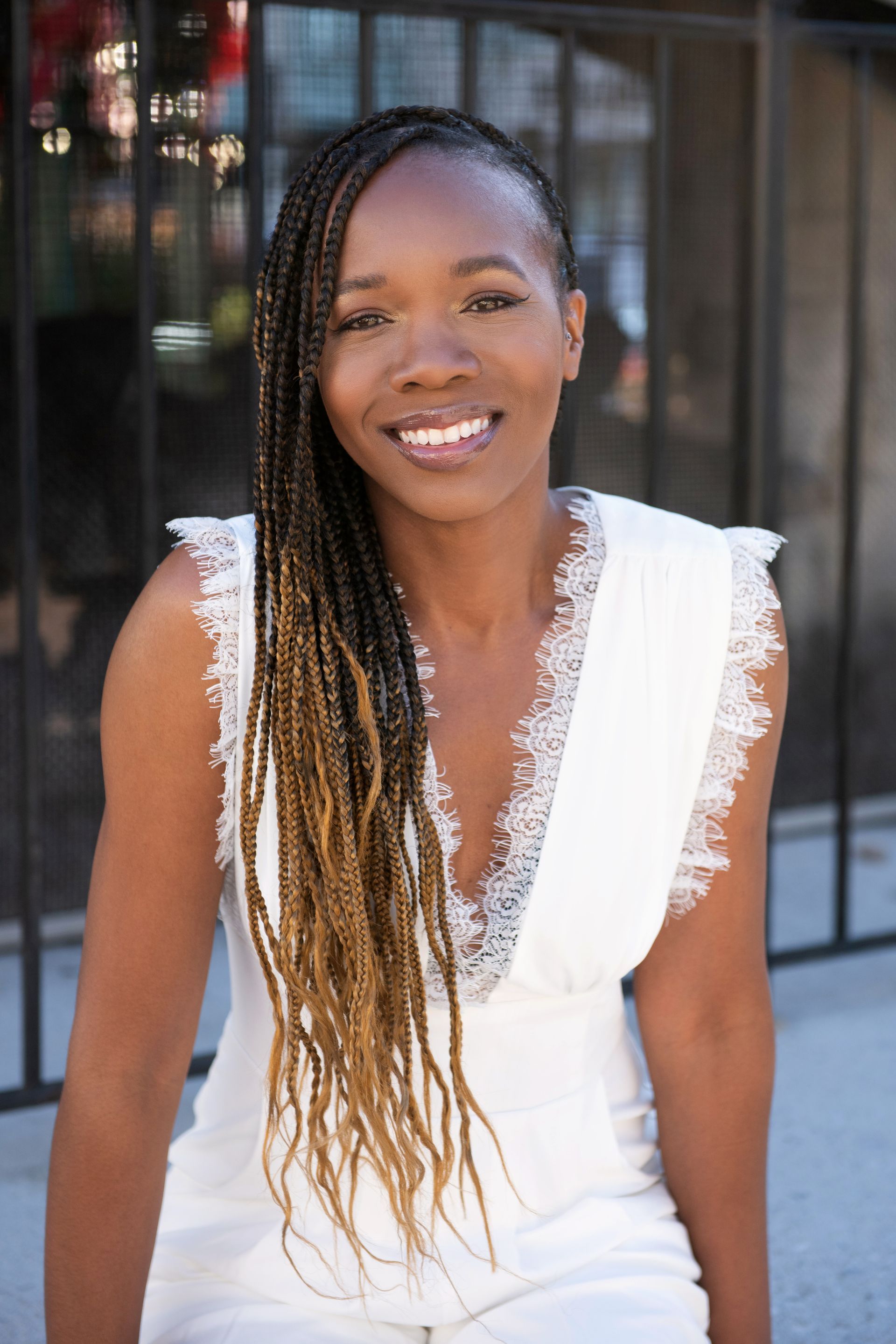 A woman is sitting outdoors in front of an outdoor fireplace.