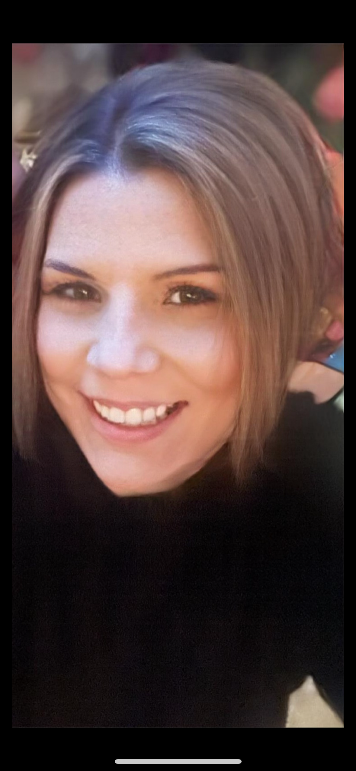 Woman wearing glasses, typing on a laptop at a desk in an office setting.