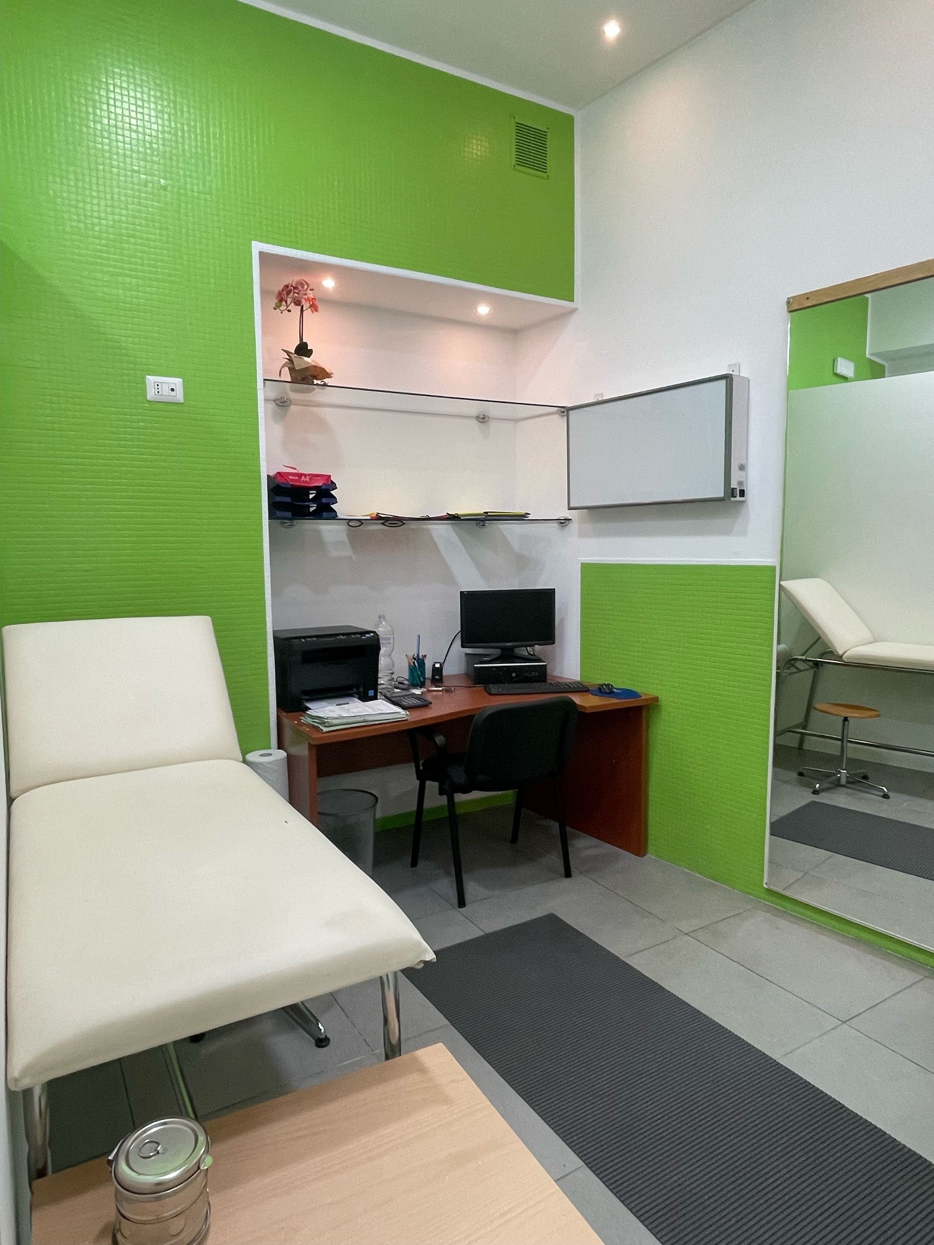 Uno studio medico con pareti verdi, una scrivania e una sedia