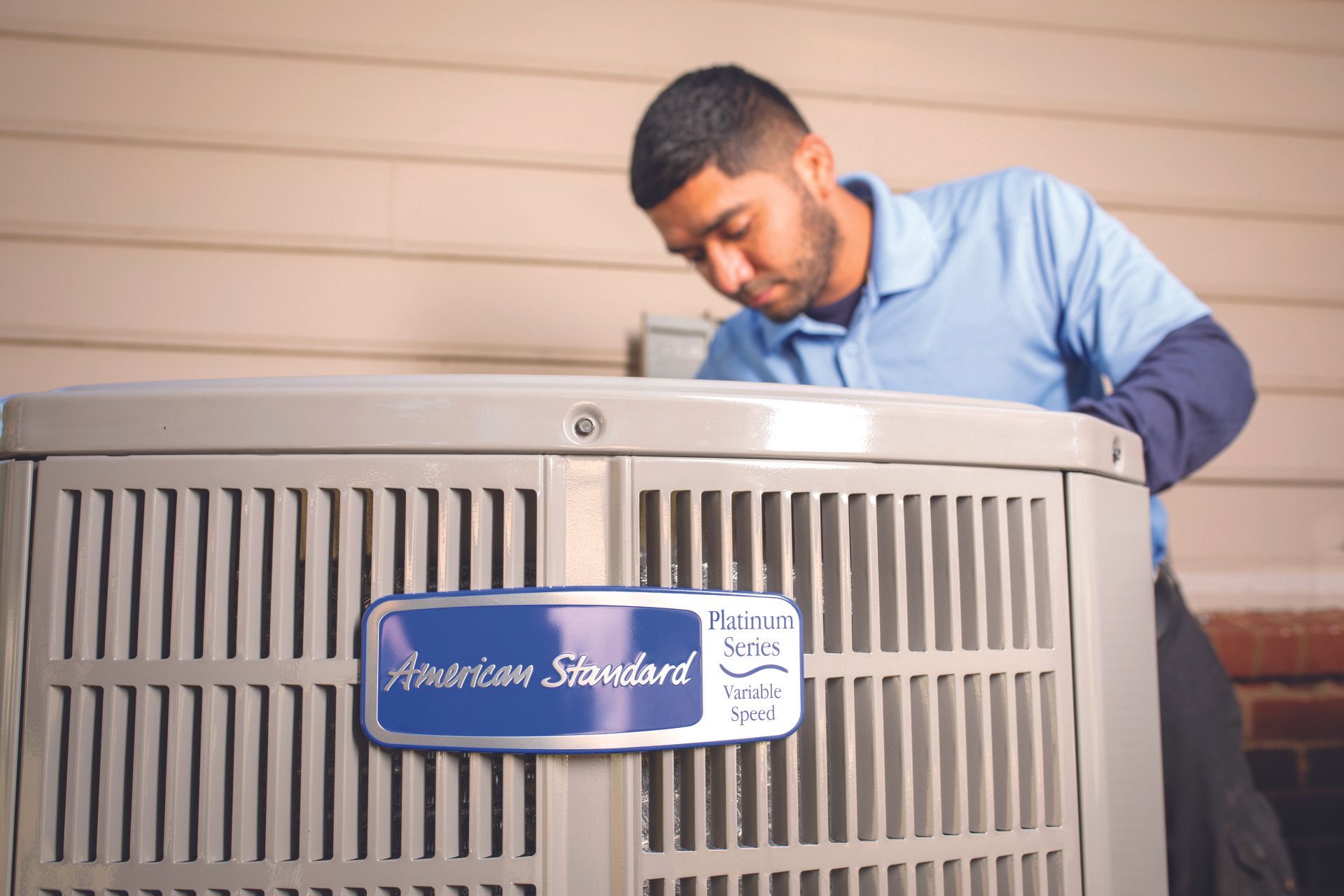 A man is working on an air conditioner outside of a house.