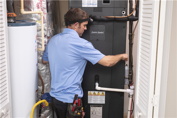 A man in a blue shirt is working on an air conditioner.