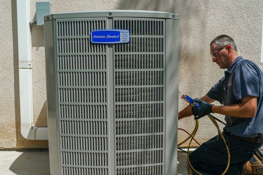 A man is working on an air conditioner outside of a building.