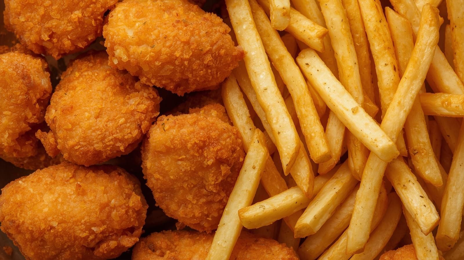 Chicken nuggets and french fries; golden-brown fried foods, close-up shot.