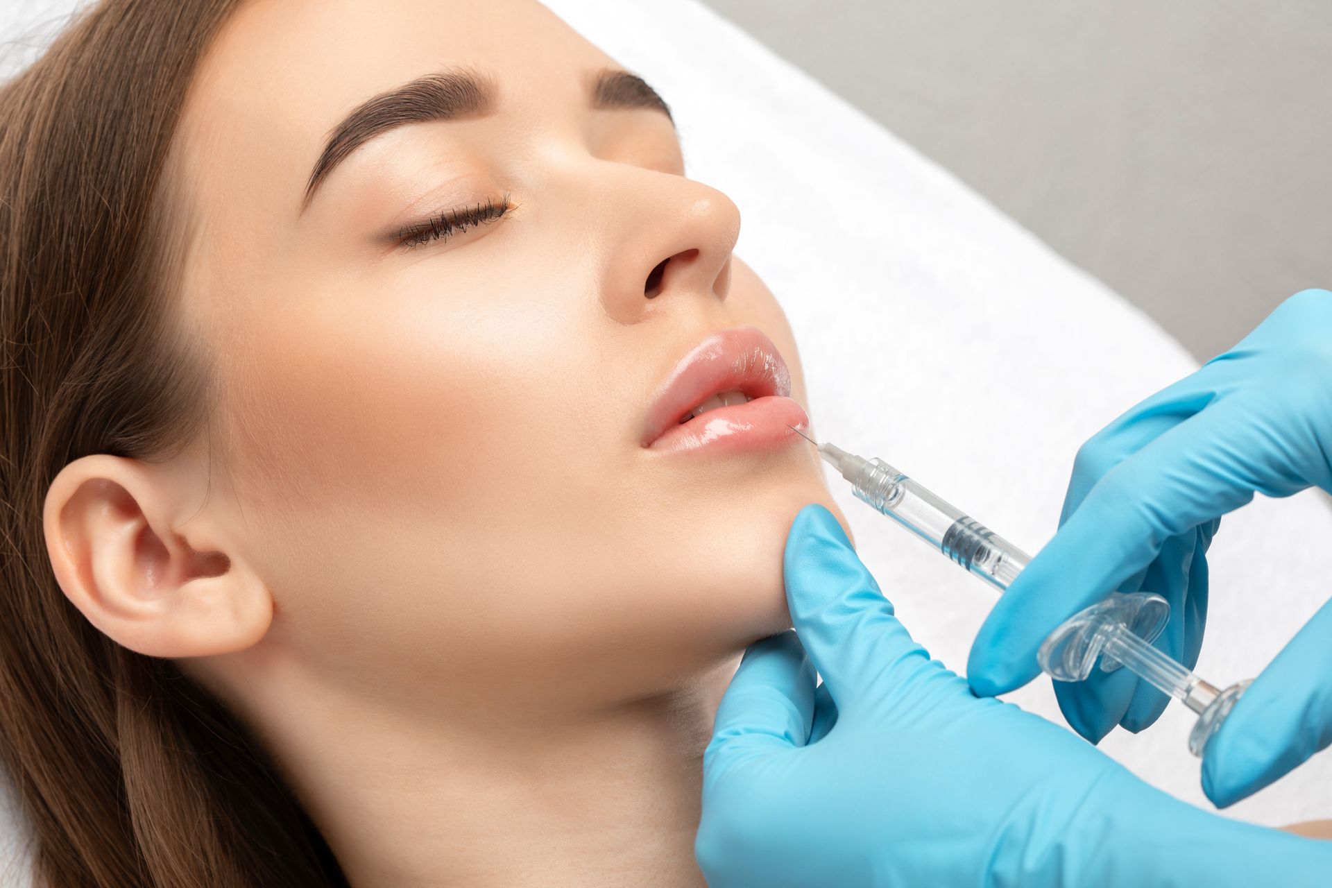 A woman is getting a botox injection in her lips.