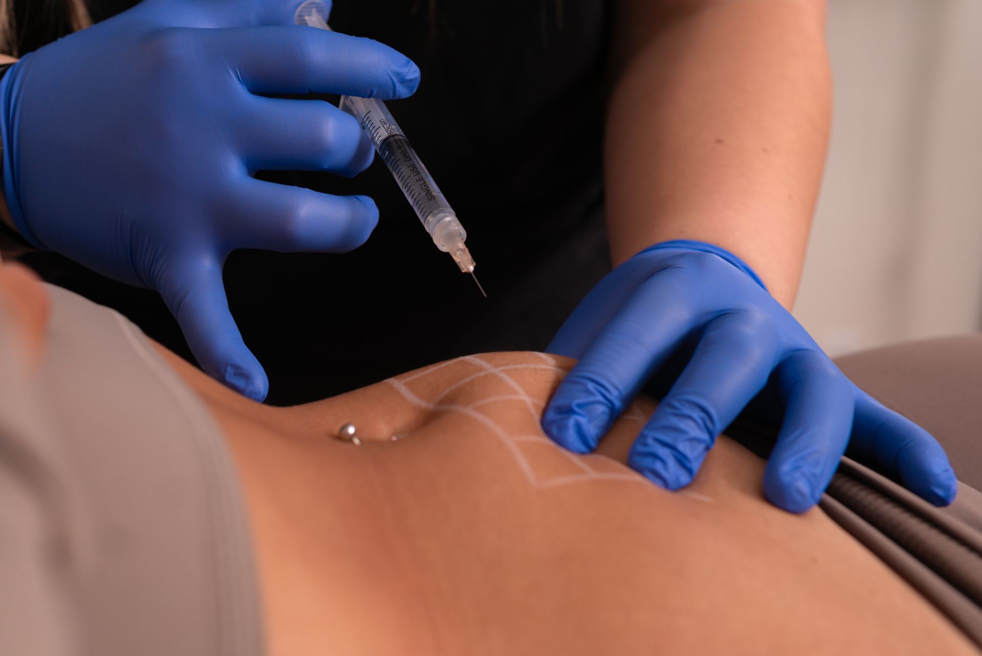 A woman is getting an injection in her stomach.