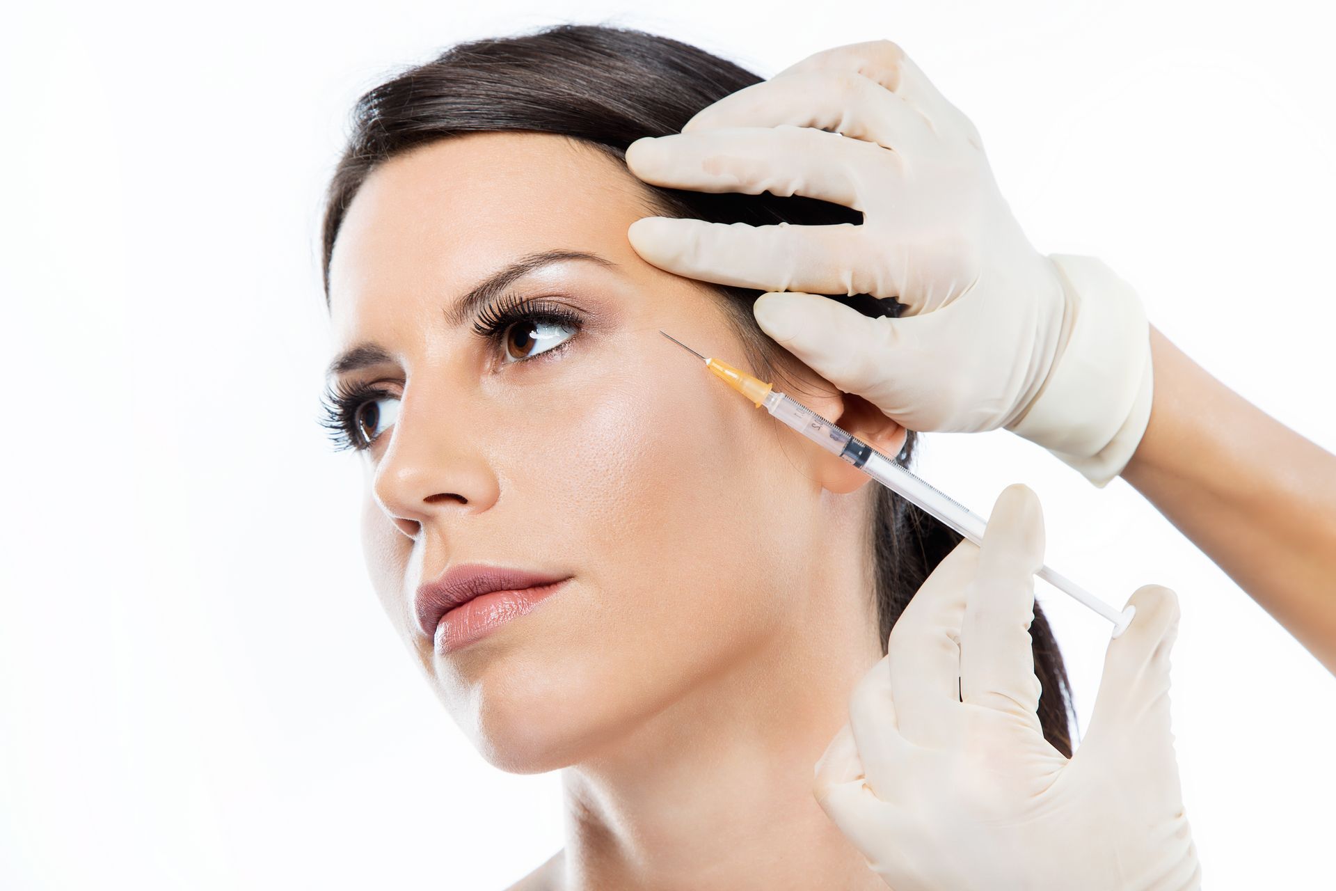 A woman is getting a botox injection in her forehead.