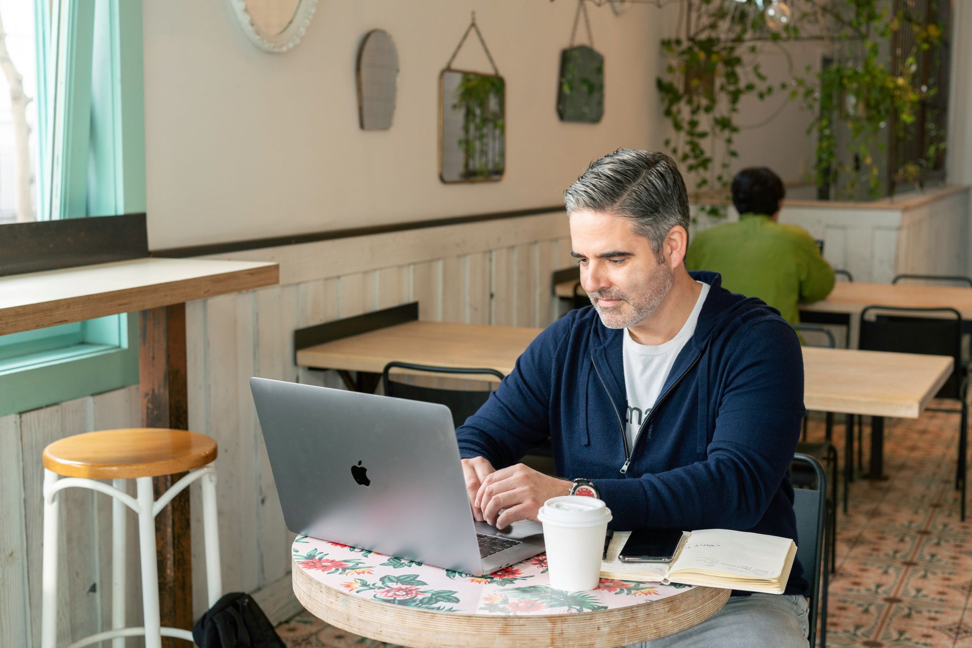 A man is sitting at a table using a laptop computer.