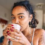 A woman with red nails is drinking from a cup.