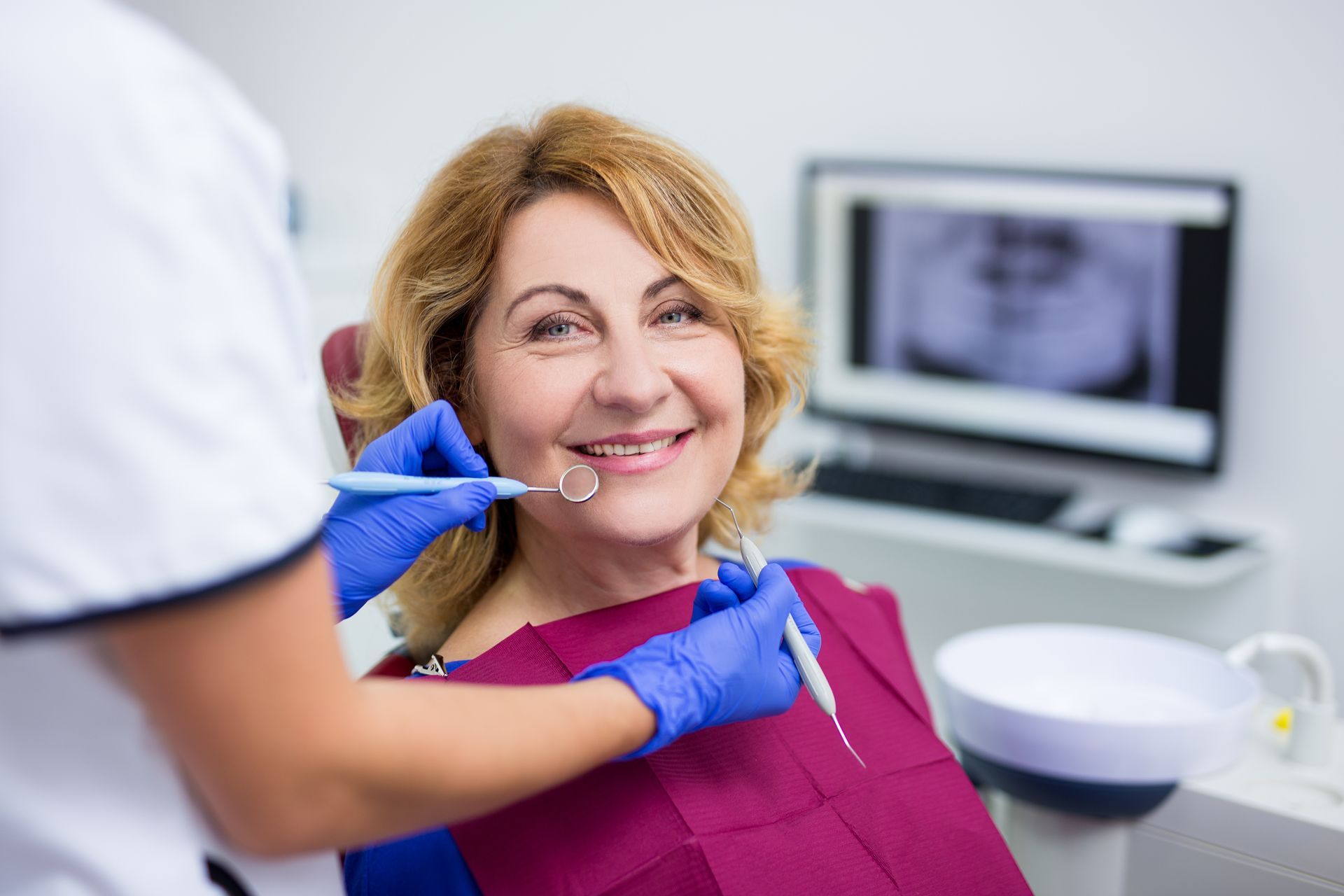 Dentist pointing to equipment, showing a patient. Blue drape and mask. Schedule an Appointment! text.