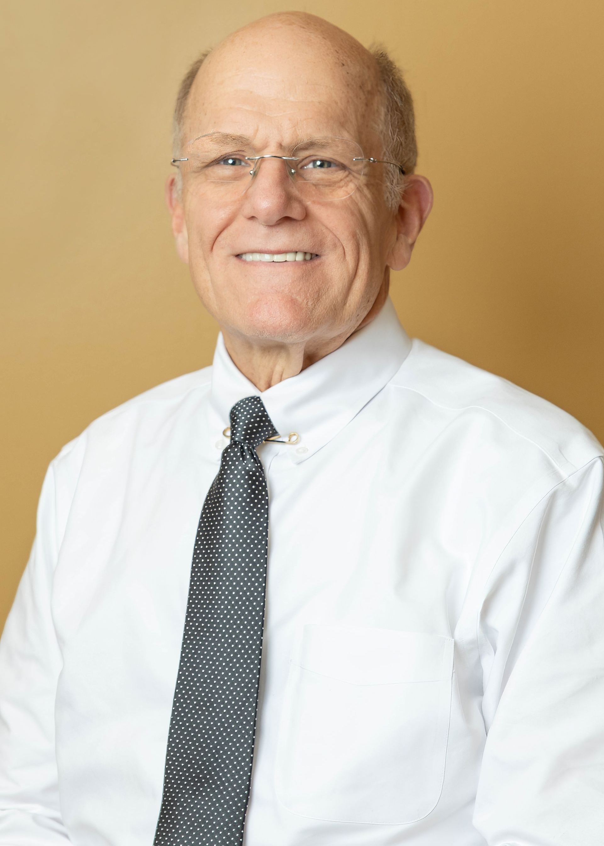 Smiling man with a beard, in a blurred indoor setting, wearing a black sweater.