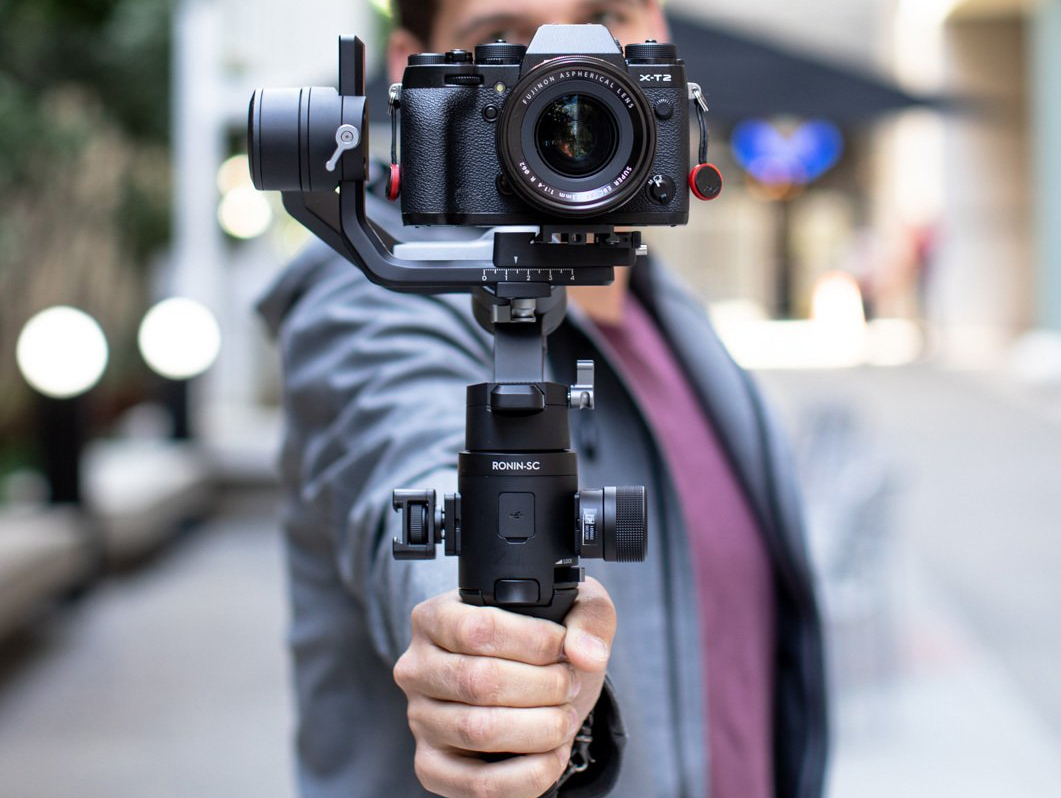 A man is holding a camera on a gimbal.