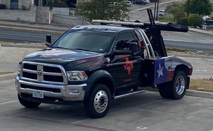 a black tow truck with a texas flag on the back