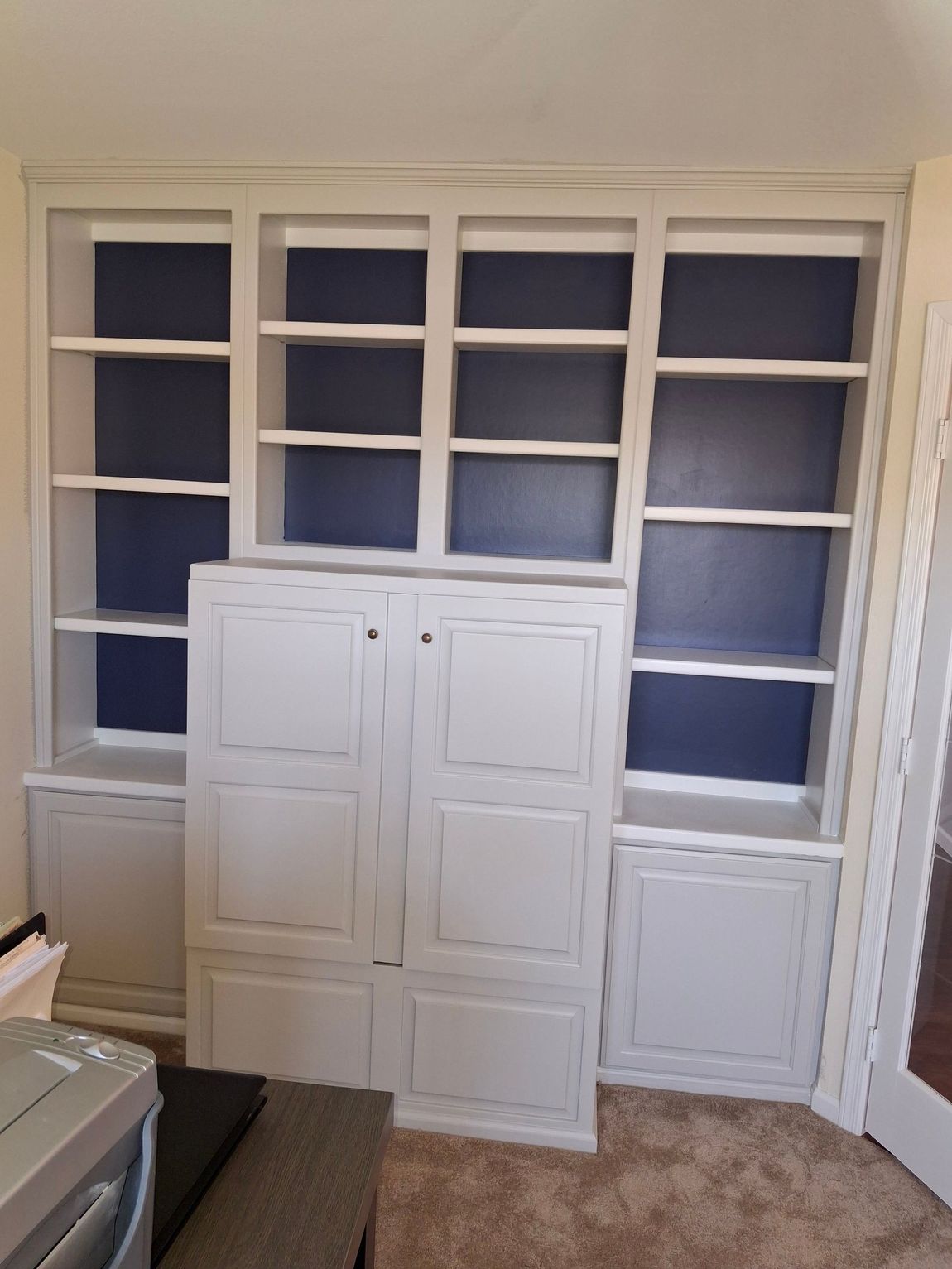 A laundry room with white cabinets and blue shelves