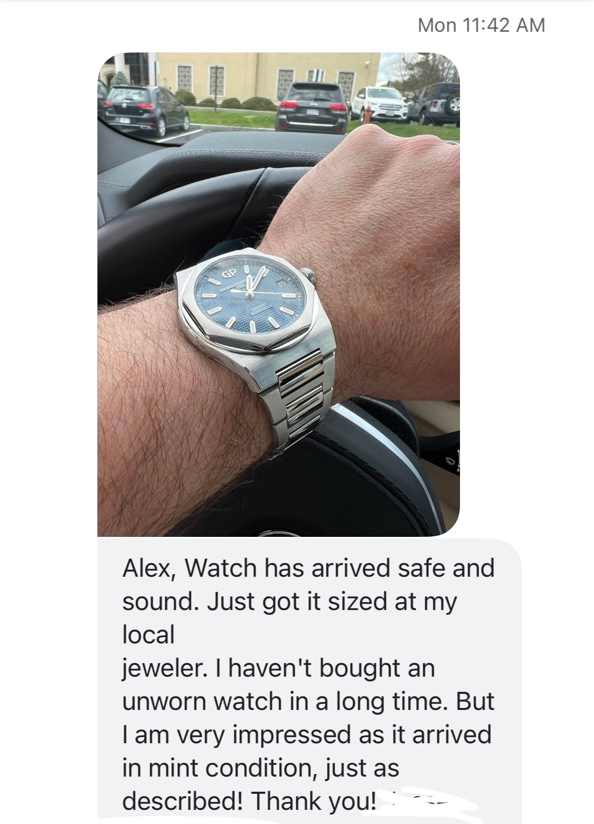 A man is driving a car and wearing a watch on his wrist.