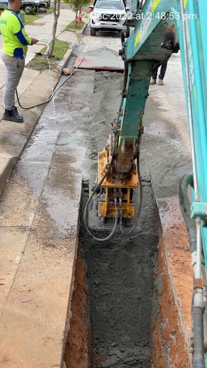 A worker operates a machine to compact concrete in a trench on a sidewalk. — All Stars Plumbing In Dapto, NSW